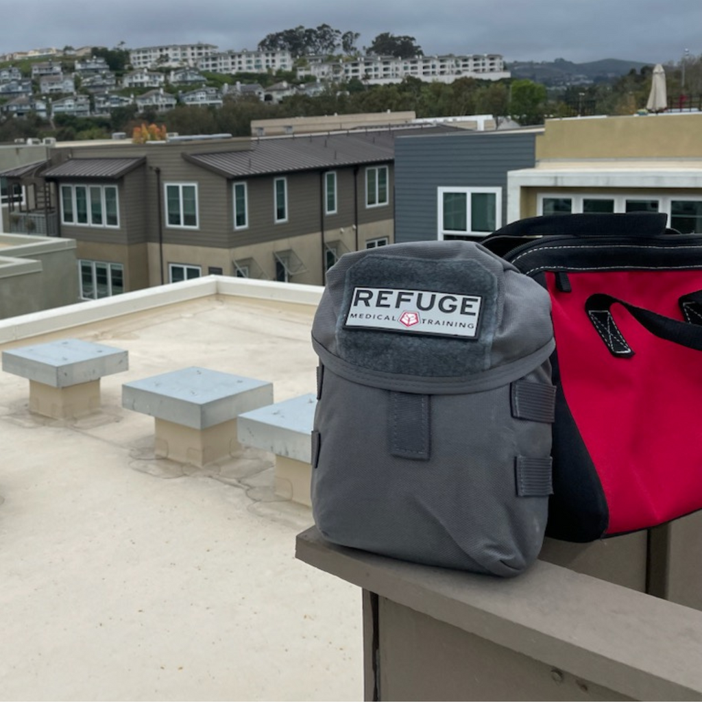 Refuge Medical BearFAK First Aid Kit -  Gray pictures on top of a roof next to a red tool bag.